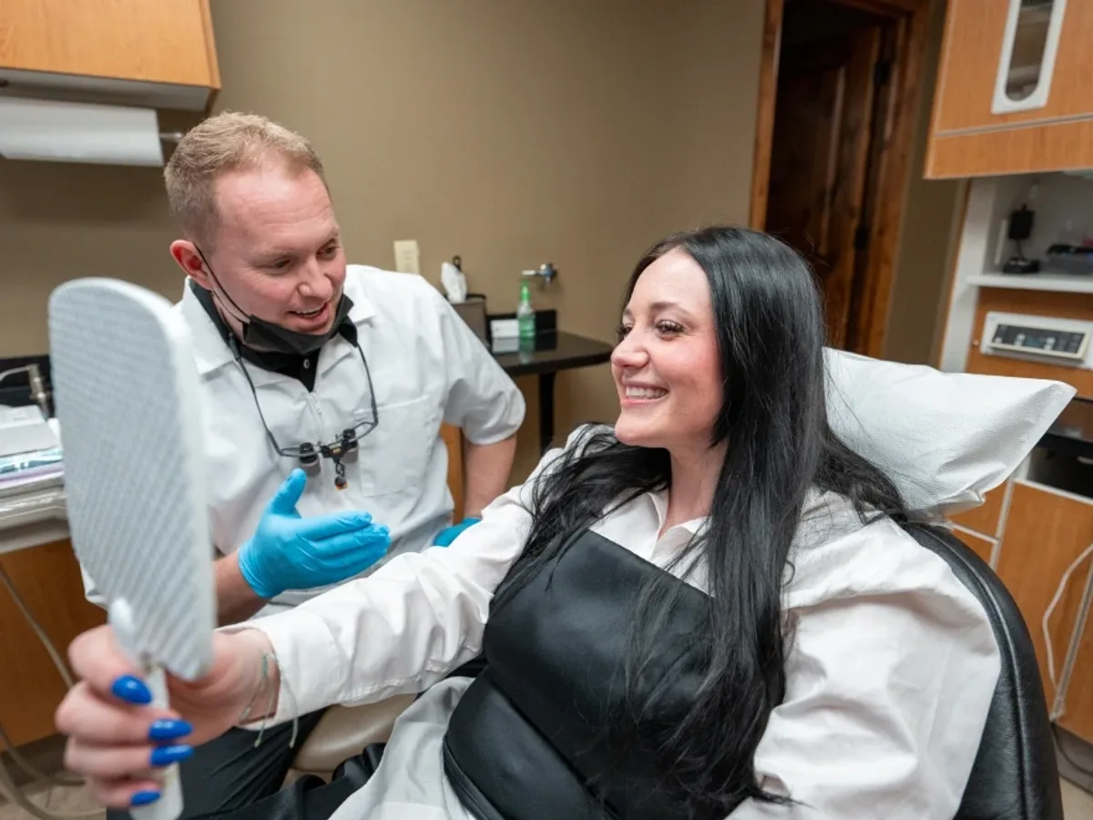 A Redwood patient reviewing her restored smile in a hand mirror | Complete Smiles-Cottonwood Heights-Mountain View-Redwood-Utah