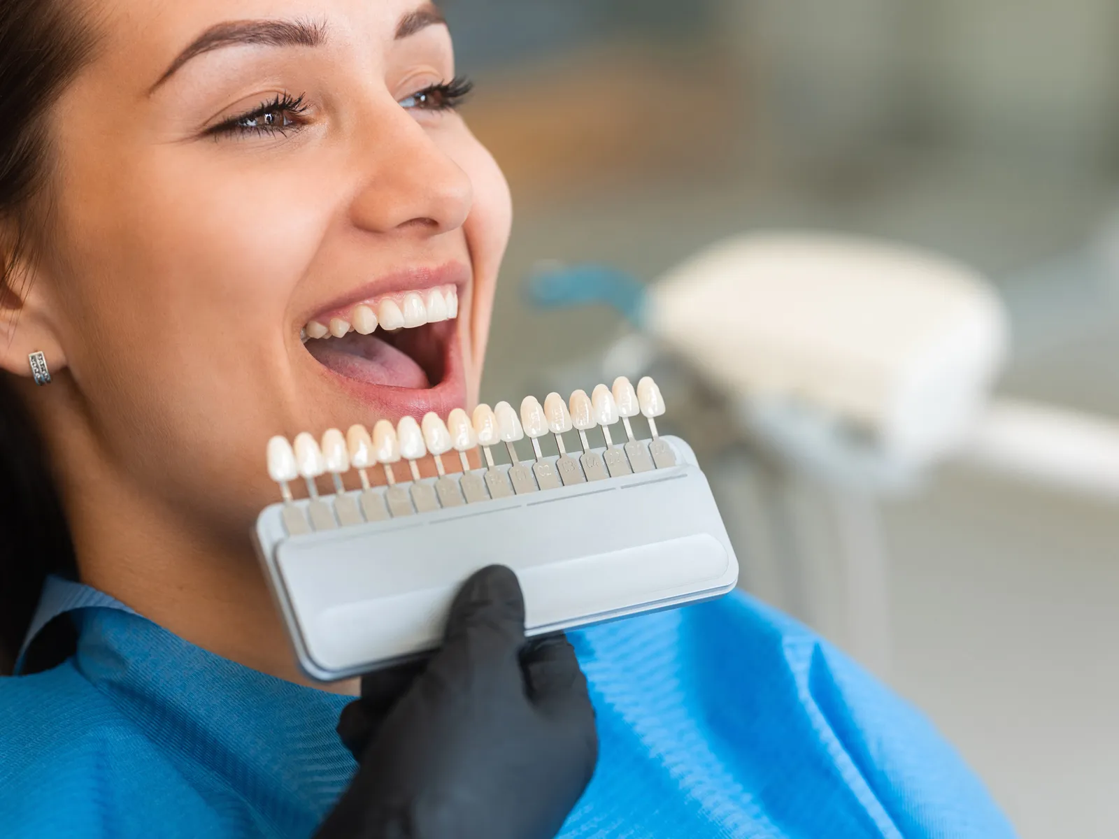 A veneer shade guide held up beside a patient’s smile | Complete Smiles-Cottonwood Heights-Mountain View-Redwood-Utah